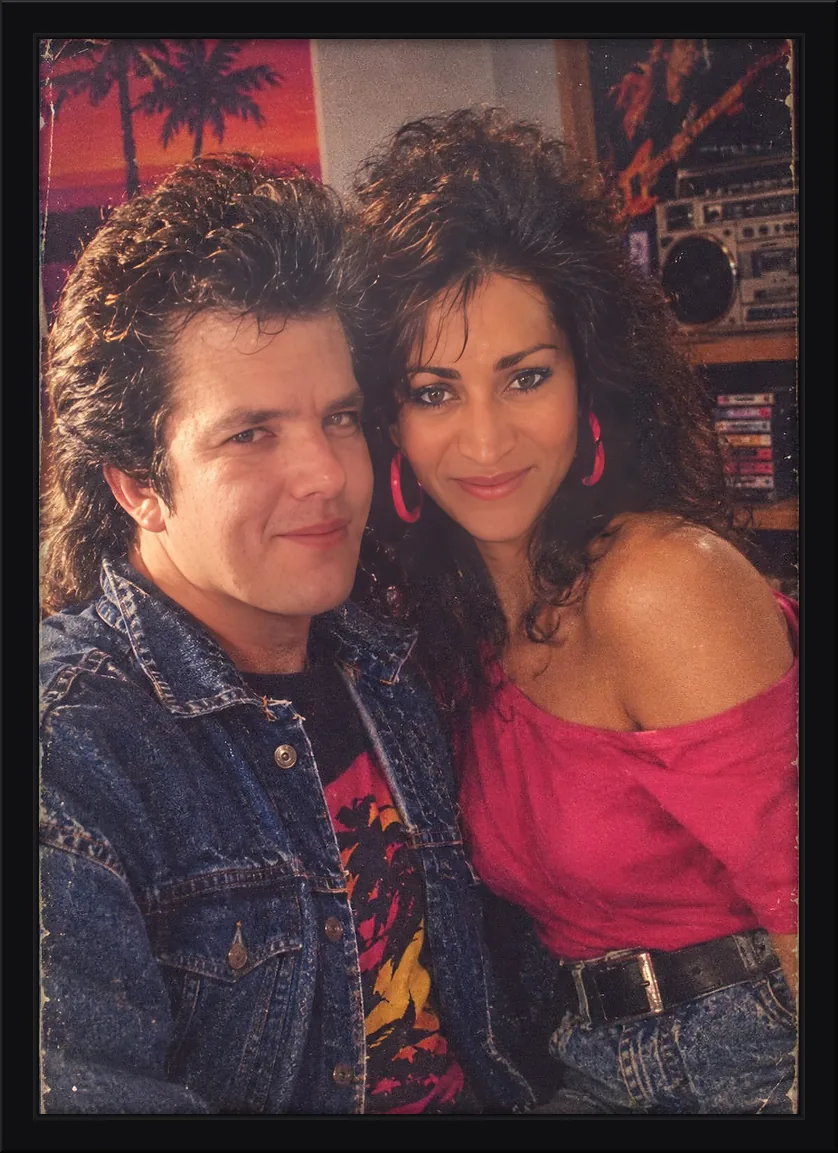Quadro decorativo de casal em visual dos anos 80 ao lado de um rádio boombox